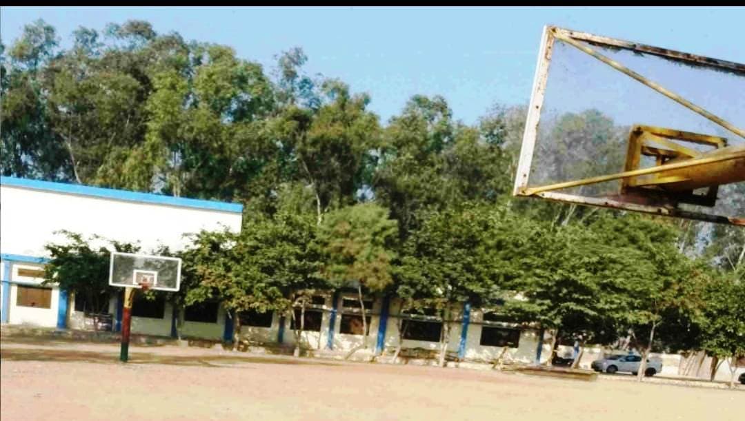Outdoor basketball court and hoop, sports block in the background